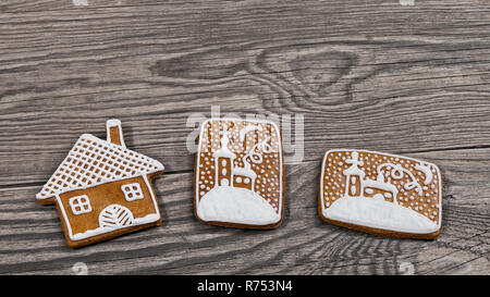 Traditional ornate Christmas gingerbreads on a wooden background. Decorative gingerbread pastries in house shape and with hand-painted chapel in snow. Stock Photo