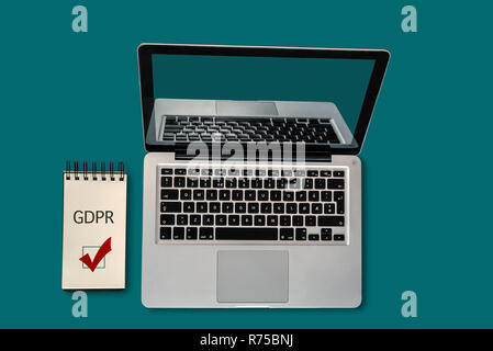 Top view of a laptop and a notepad with GDPR and a ticked checkbox on it, with copyspace