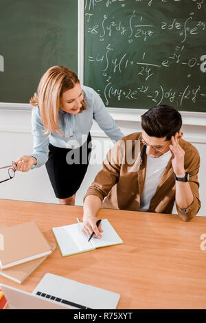 Female teacher speaking with young student in classroom Stock Photo