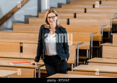 beautiful female university professor smiling and looking at camera in classroom Stock Photo