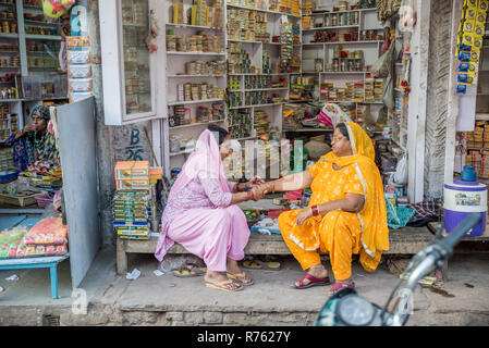 Two ladies sitting in front of a small shop in Bikaner, Rajasthan, India Stock Photo