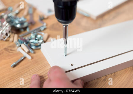 Assembling furniture from chipboard, using a cordless screwdriver Stock Photo