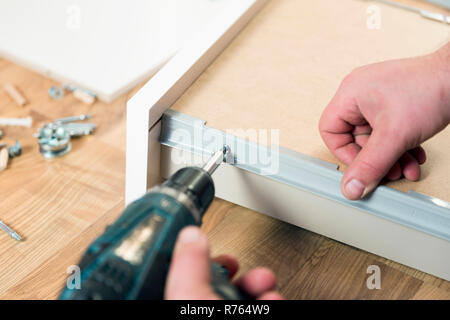 Assembling furniture from chipboard, using a cordless screwdriver Stock Photo