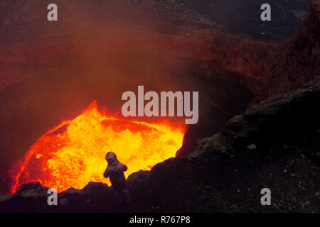 A man in a protective suit near the mouth of the volcano. Investigation of the volcano Stock Photo
