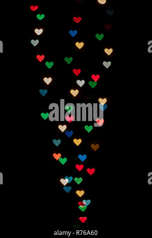 Heart shaped qustom bokeh created from decoration lights and isolated on black background. Stock Photo