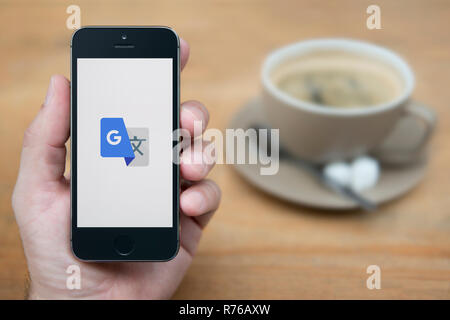 A man looks at his iPhone which displays the Google Translate logo (Editorial use only). Stock Photo
