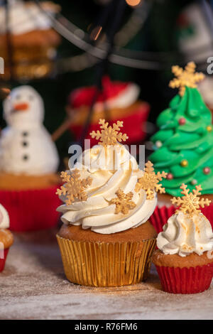 Various colorful Christmas cupcakes with christmas tree and wood background Stock Photo