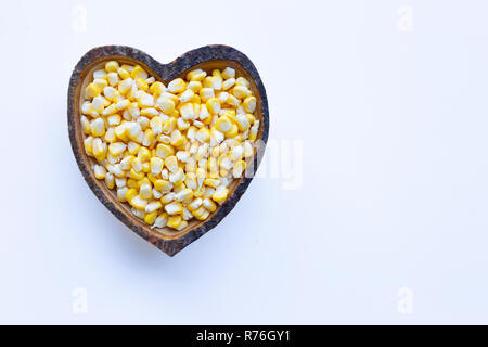 Corn seeds in wooden heart shape dish on white background Stock Photo