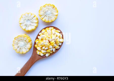 Corn seeds on wooden spoon and ripe corn cobs on on white background Stock Photo