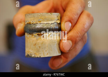 Metal pipe with a welded seam In the hand of a welder's man. Stock Photo
