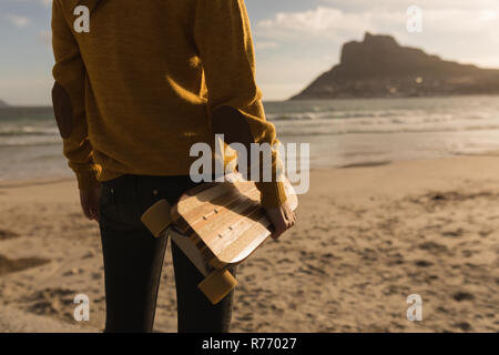 Woman standing with skateboard on beach Stock Photo