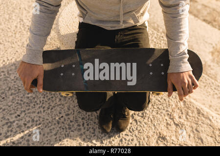 Woman sitting with skateboard on beach Stock Photo
