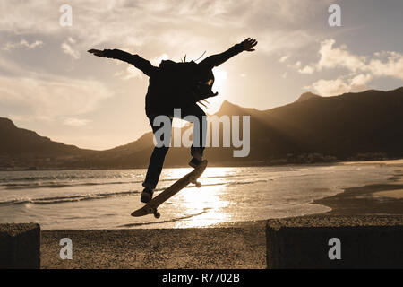Woman skateboarding on wall at beach Stock Photo