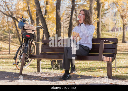 Man having coffee while sitting on a bench in the park Stock Photo
