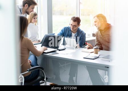 Sharing opinions. Group of young modern people in smart casual wear discussing business while working in the creative office Stock Photo