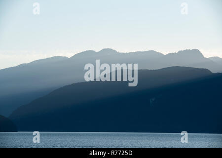 Sun's rays pour over the beautifully illuminated mountains of the Coast Mountain Range in the late afternoon. Stock Photo