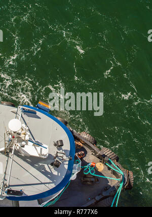 Overhead POV view of tugboat, ropes and workers assisting large ship to dock in high winds on a bright sunny day. Gastineau Channel, Juneau, Alaska, U Stock Photo