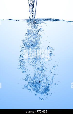 Pouring water splash with air bubbles in blue white water background Stock Photo