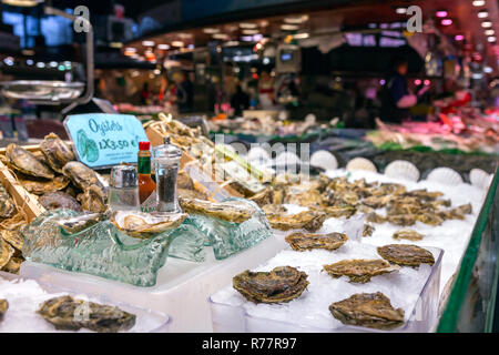 Opened fresh oysters on ice with lemon at the Mercat de Sant Josep de la Boqueria, a large public market in the Ciutat Vella district in Barcelona, Sp Stock Photo