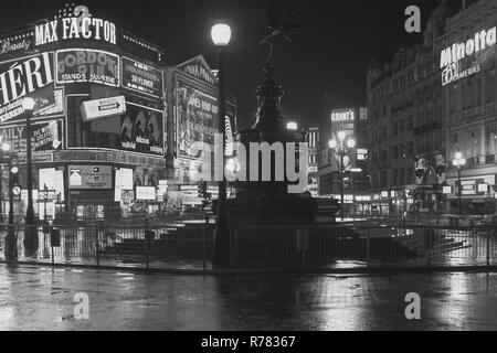 1969, a wet central London night, seen here is the Shaftesbury Memorial Fountain, more commonly known as statue of eros at Piccadilly Circus, with the neon lights of the surrounding advertising billboards. Showing at the London Pavilion, the new James Bond film, 'On Her Majesty's Secret Service', the sixth film in the Bond 007 series. Stock Photo
