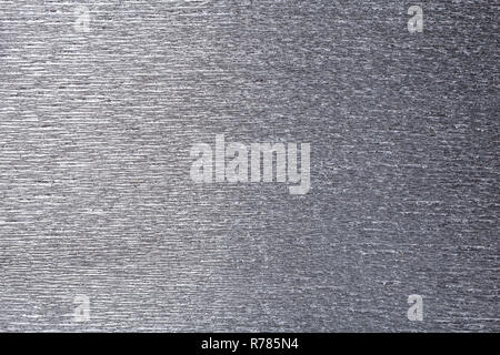 Textural of gray foil background of wavy corrugated paper, closeup. Structure of metallic wrinkled crepe silver cardboard macro. Stock Photo