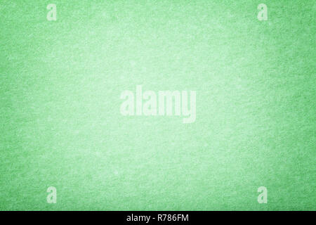 Light green matte background of suede fabric, closeup. Velvet texture of seamless mint woolen felt with vignette. Stock Photo