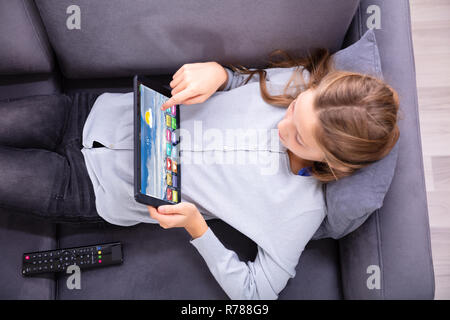 Elevated View Of A Girl Lying On Sofa Using Digital Tablet Stock Photo