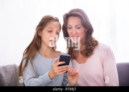 Portrait Of Mature Mother With Her Daughter Using Cellphone Stock Photo