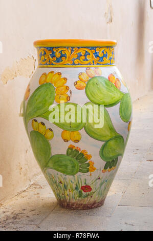 Ceramic jar decorated with floral motifs in cactus leaves laid on the ground Stock Photo