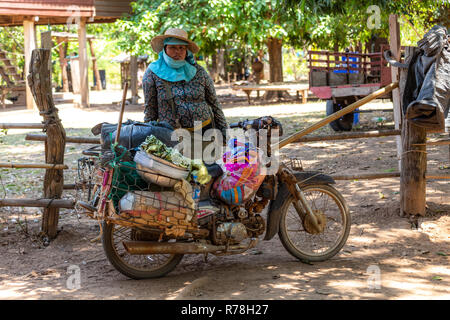 Don Daeng, Laos - April 27, 2018: Senior woman posing with a vintage scooter in a remote rural area of Laos Stock Photo