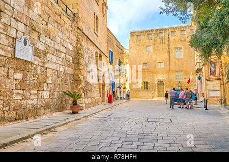 MDINA, MALTA - JUNE 14, 2018: The Mdina rd. square with its huge medieval edifices located right after the Gates, welcomes visitors of the Citadel, on Stock Photo