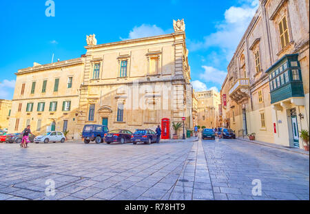 MDINA, MALTA - JUNE 14, 2018: The urban scene on St Paul Square with old medieval edifices with retro style red telephone booth, on June 14 in Mdina. Stock Photo