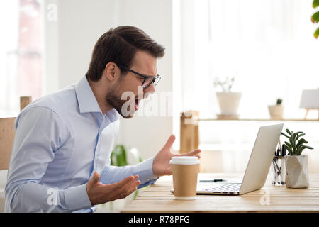 Furious male employee have laptop problems while working Stock Photo