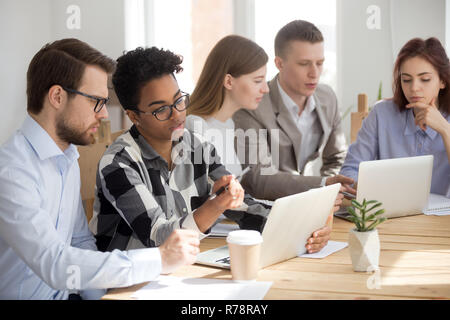 Multiethnic employees use laptops working in teams Stock Photo