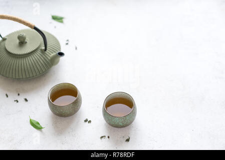 Asian Tea Set -  iron teapot and ceramic teacups with green tea. Traditional tea composition on white background, copy space. Stock Photo