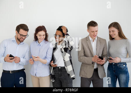 Diverse young people in queue communicate using smartphones Stock Photo