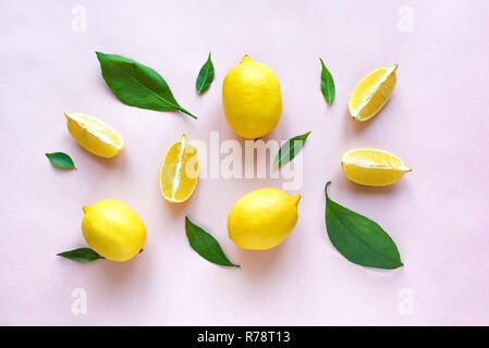 Lemons with green leaves on pink pastel background, top view, flat lay. Organic fresh citrus fruits lemons, minimal conceptual flat lay. Stock Photo