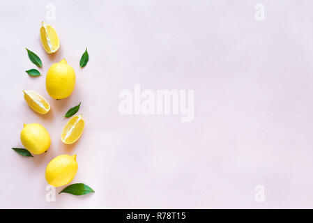 Lemons with green leaves on pink pastel background, top view, copy space. Organic fresh citrus fruits lemons, minimal conceptual flat lay. Stock Photo