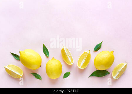 Lemons with green leaves on pink pastel background, top view, copy space. Organic fresh citrus fruits lemons, minimal conceptual flat lay. Stock Photo