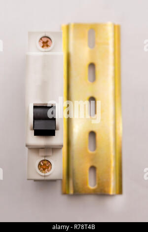 a light switch, a plastic mechanical switch of white color installed on a light gray wall Stock Photo