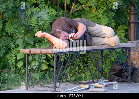 Depressed drunk man asleep outdoor on a park bench with beer bottles - Russia Berezniki 15 July 2018 Stock Photo