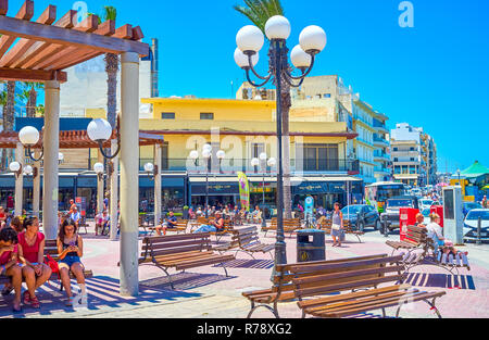 BUGIBBA, MALTA - JUNE 14, 2018: The Bugibba Square is the center of the rest in the heart of resort due to numerous benches, some of them are under th Stock Photo