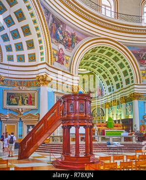 MOSTA, MALTA - JUNE 14, 2018: The unusual Basilica Rotunda boasts beautiful decoration of its interior, such as carved plaster on the arches and huge  Stock Photo