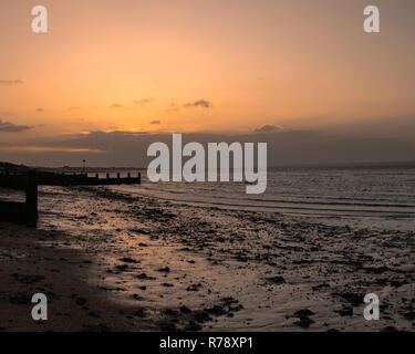 Sunset on a Uk beach with wooden beach Groynes Stock Photo