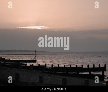 Sunset on a Uk beach with wooden beach Groynes Stock Photo