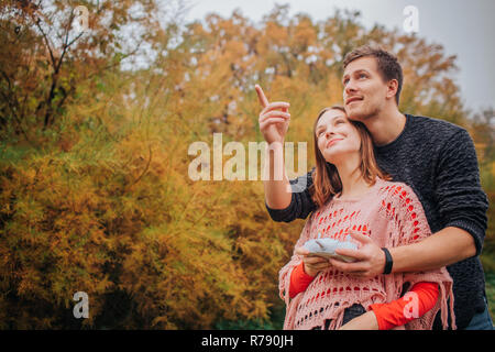 Happy and positive couple stand and look up. He points. They hold remote control together. Stock Photo