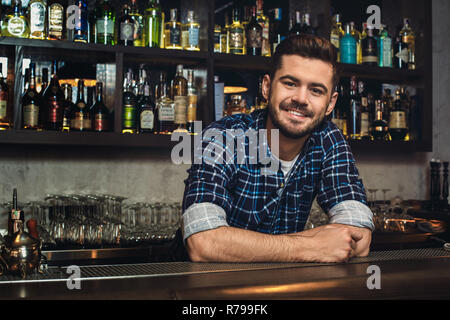 Young bartender leaning at bar counter smiling cheerful Stock Photo