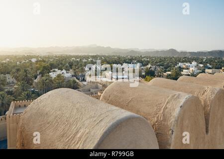 City against mountain range at idyllic sunset. Nizwa in Sultanate of Oman. Stock Photo