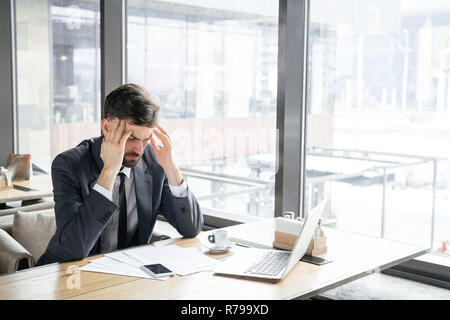 Businessperson on business lunch at restaurant sitting near window having headache Stock Photo