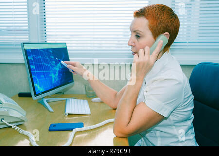 Beautiful girl stock broker talking on the phone in the office Stock Photo